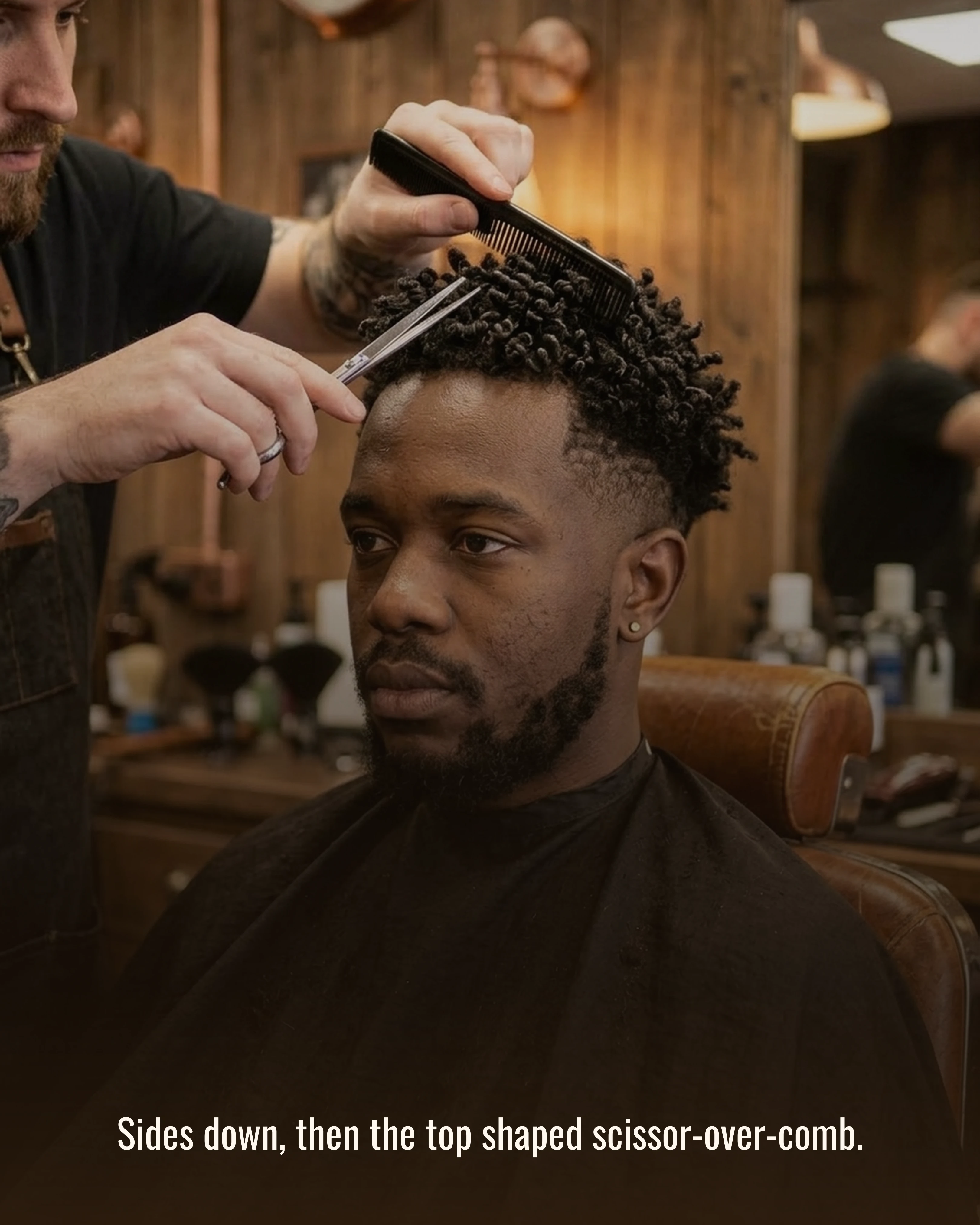 The barber shaping the top scissor-over-comb after taking the sides down